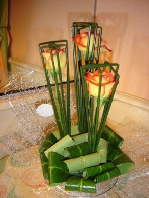 6 orange Roses enclosed individually in a cage made of sticks with a base of curled leaves