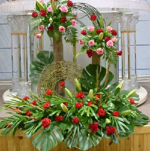 Pink and Red roses arranged in a large flat basket with elevated two pillars at different heights covered with roses enhanced with round jute